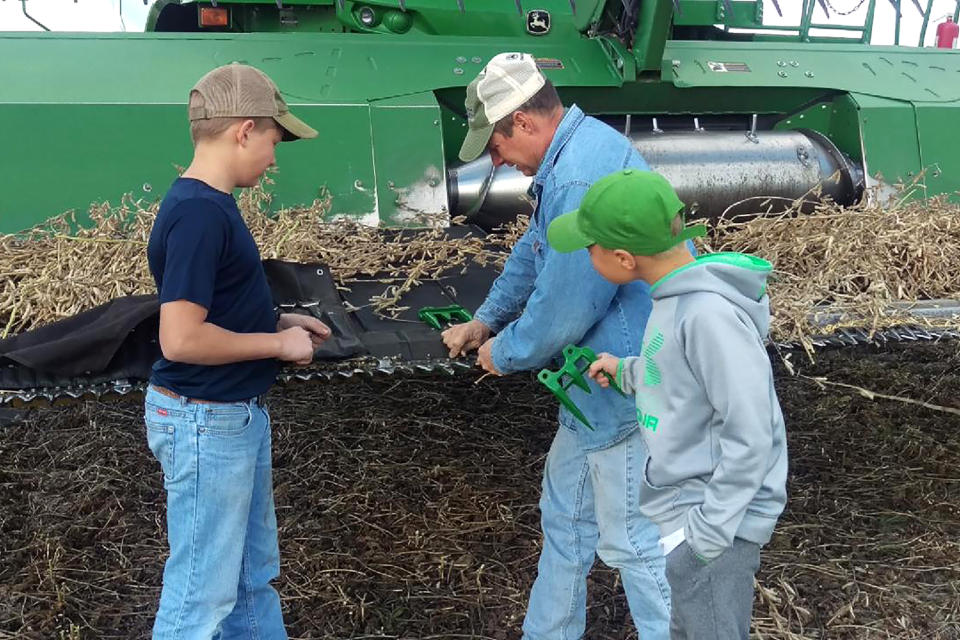 Image: David Misener works on a combine harvester with his sons. (Courtesy David Misener)