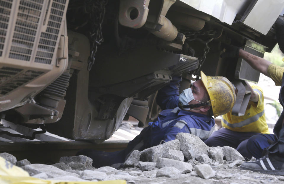 A worker comes out from under the derailed train near Taroko Gorge in Hualien, Taiwan on Saturday, April 3, 2021. The train partially derailed in eastern Taiwan on Friday after colliding with an unmanned vehicle that had rolled down a hill, killing and injuring dozens. Workers began removing some of the train cars and repair work also has begun on the tracks including the tunnel where part of the eight-car train crashed. (AP Photo/Chiang Ying-ying)