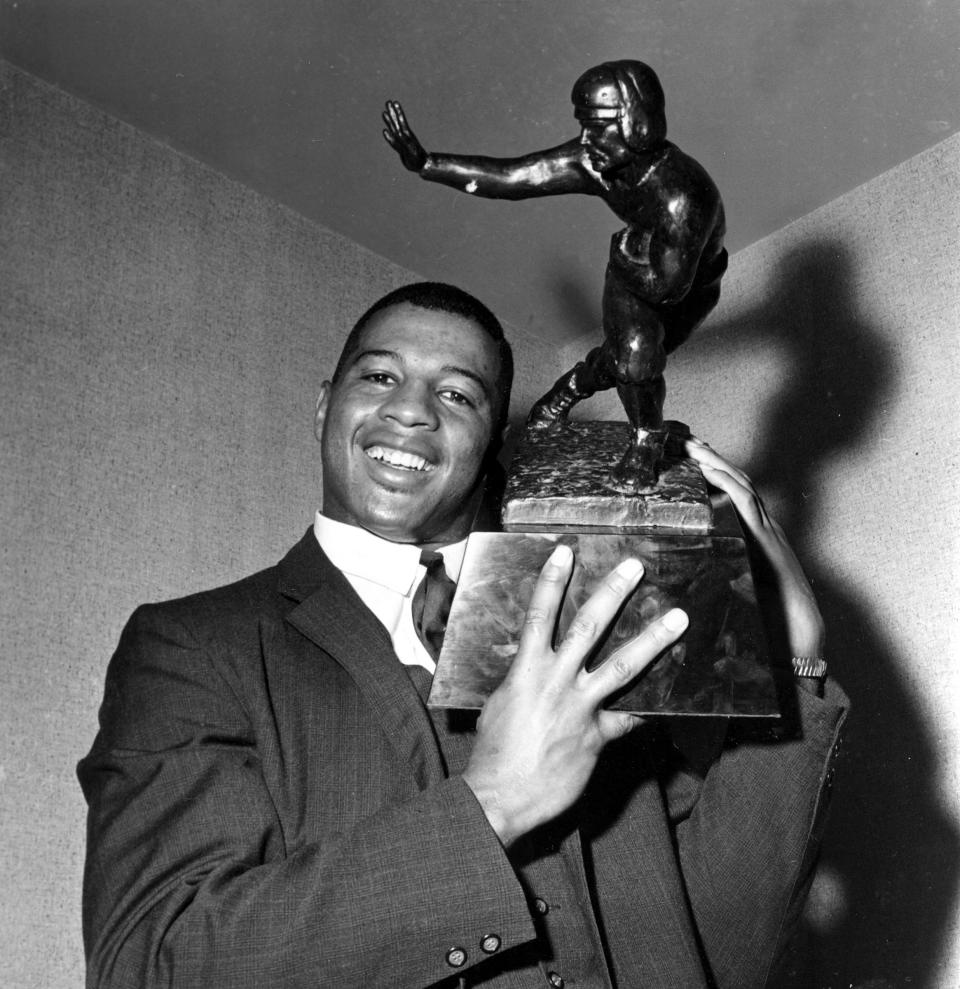 FILE - Ernie Davis, halfback for Syracuse, holds the Heisman Trophy prior to official presentation to him in New York City, in this Dec. 6, 1961, file photo. Syracuse was one of the standard-bearers in terms of accepting athletes based on performance and ability. Its history includes: Wilmeth Sidat-Singh, a quarterback and the first star Black athlete at the school in the 1930s; Bernie Custis, who quarterbacked the Orange from 1948-50 and became the first Black professional quarterback in the modern era with the Hamilton Tiger-Cats of the Canadian Football League; Jim Brown, regarded by many as the greatest running back of all time, starred at Syracuse in the mid-1950s and has dedicated much of his life to issues of social justice; and former Orange tailback Ernie Davis, the first Black to win the Heisman Trophy (1961). (AP Photo/File)