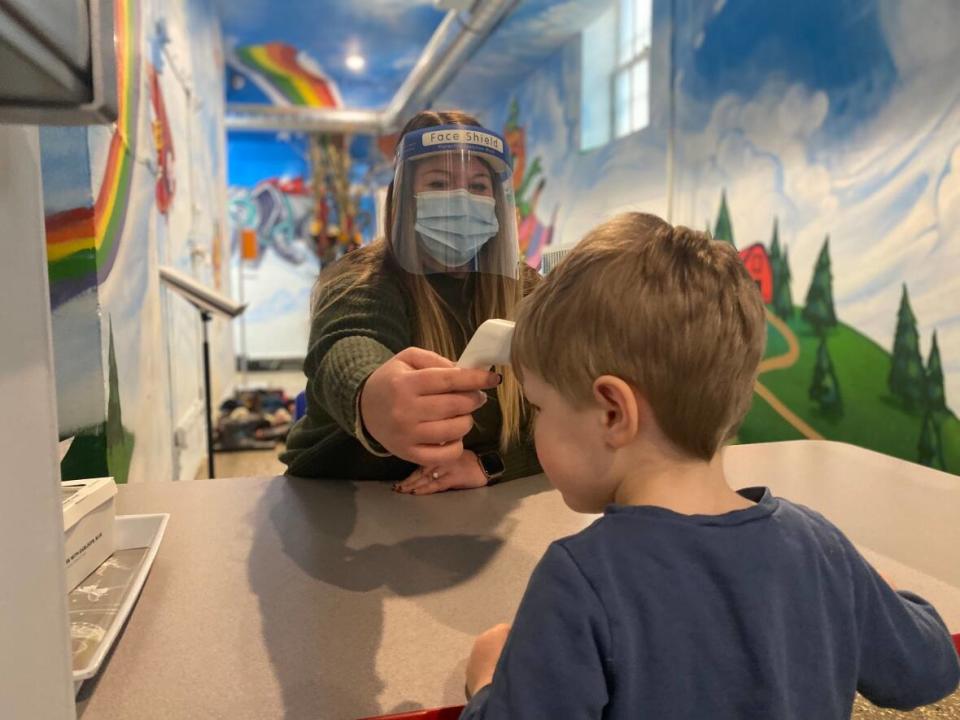 A staffer at Momentum Montessori, a daycare centre in Toronto, takes a child's temperature on Thursday, January 13, 2022. (Natalie Edwards/Momentum Montessori - image credit)