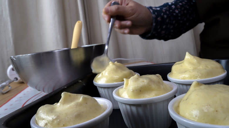 Person filling soufflé ramekins