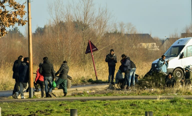 Migrants gathered near a truck parking lot along the highway that leads to the ferry terminal at Calais, France, a few days before President Emmanuel Macron's visit to the city Tuesday