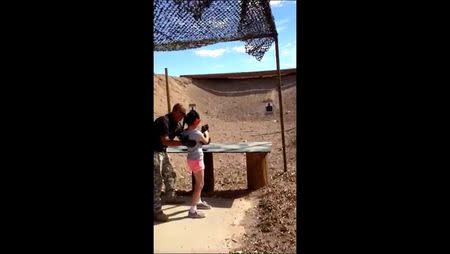 Shooting instructor Charles Vacca stands next to a 9-year-old girl at the Last Stop shooting range in White Hills, Arizona near the Nevada border, on August 25, 2014, in this still image taken from video courtesy of the Mohave County Sheriff's Office. REUTERS/Mohave County Sheriff's Office/Handout via Reuters