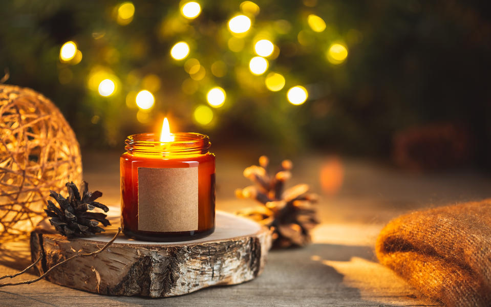 lit Christmas candle on a piece of wood with pine cones