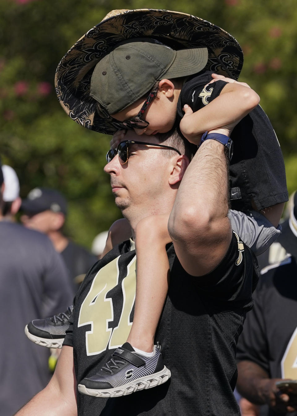 Orlan Lockhart, of Prairieville, La., holds his son Orlan Lockhart, Jr., 5, at the start of the Back Together Weekend fan appreciation initiative at the New Orleans Saints NFL team's football training camp in Metairie, La., Saturday, July 29, 2023. (AP Photo/Gerald Herbert)