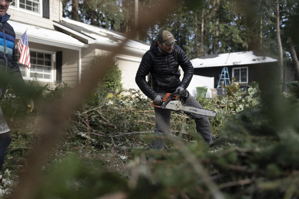 Justin Brooks works on clearing trees that fell around his home on Tuesday, Jan. 16, 2024, in Lake Oswego, Ore. (AP Photo/Jenny Kane)