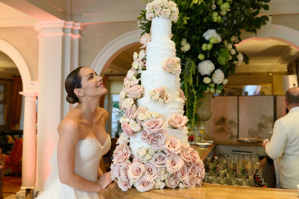 The bride posing with her six-layer wedding cake.