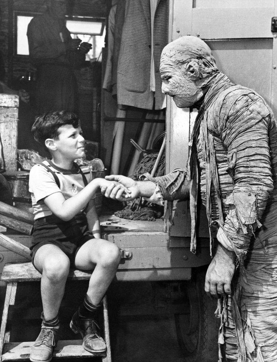 A man in a mummy suit shakes a child's hand