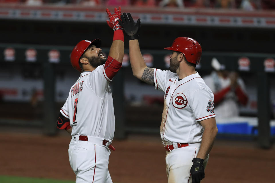Cincinnati Reds' Eugenio Suarez, left, celebrates after hitting a two-run home run with teammate Mike Moustakas, right, in the sixth inning during a baseball game against the Milwaukee Brewers in Cincinnati, Monday, Sept. 21, 2020. (AP Photo/Aaron Doster)
