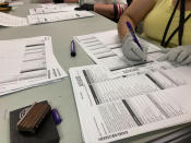 Workers check ballots at elections offices in Clackamas County, Oregon, the state's third most populous county south of Portland, Tuesday, May 17, 2022. Many ballots in the county were printed with blurry barcodes, preventing them from being read by voting tabulation machines. Workers, one Democrat and one Republican per pair, are re-recording votes from the blurred ballots on new ballots so they can be read. The problem may cause significant delays in vote-counting in a county that includes parts of two Congressional districts, including one with a competitive Democratic primary. (AP Photo/Gillian Flaccus)