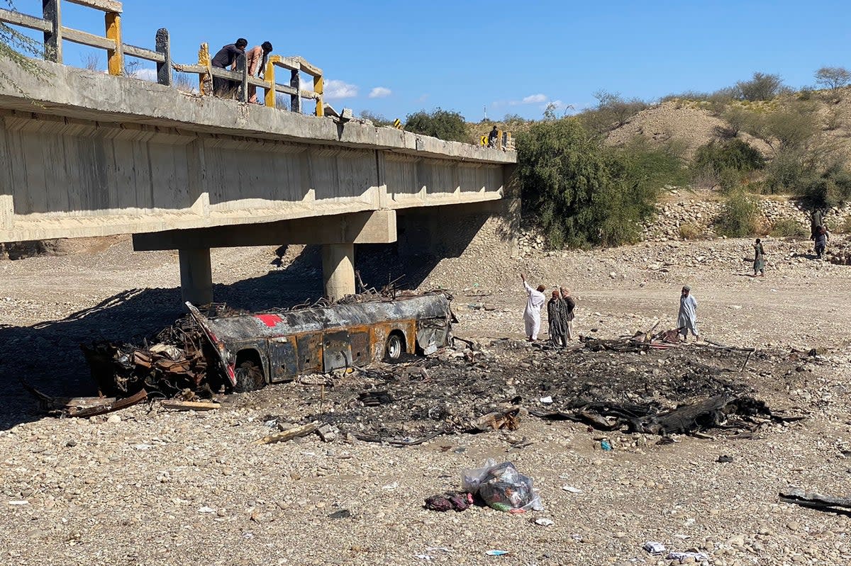 Residents look at the wreckage of a burnt passenger bus at Bela in Lasbela district of Pakistan’s Balochistan province (AFP via Getty)