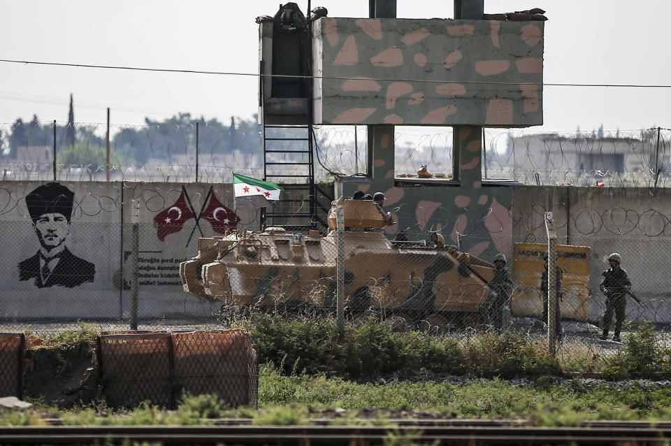 Turkish-backed Syrian opposition fighters on an armoured personnel carrier drive to cross the border into Syria, in Akcakale, Sanliurfa province, southeastern Turkey, Friday, Oct. 18, 2019. Fighting continued in a northeast Syrian border town at the center of the fight between Turkey and Kurdish forces early Friday, despite a U.S.-brokered cease-fire that went into effect overnight. (AP Photo/Emrah Gurel)