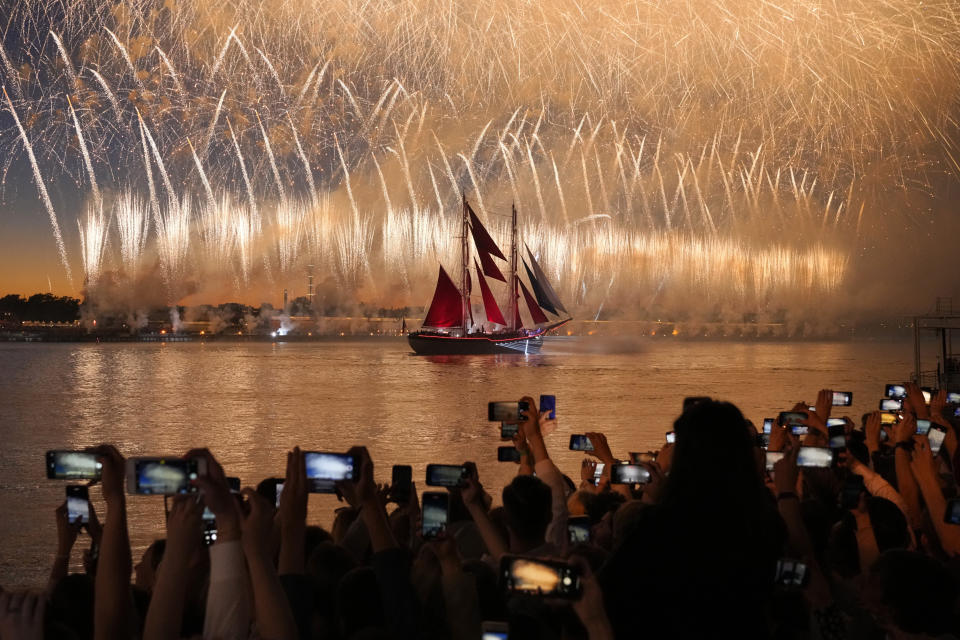 People watch fireworks and a brig with scarlet sails sailing on the Neva River during the Scarlet Sails festivities marking school graduation in St. Petersburg, Russia, early Saturday, June 25, 2022. (AP Photo/Dmitri Lovetsky)