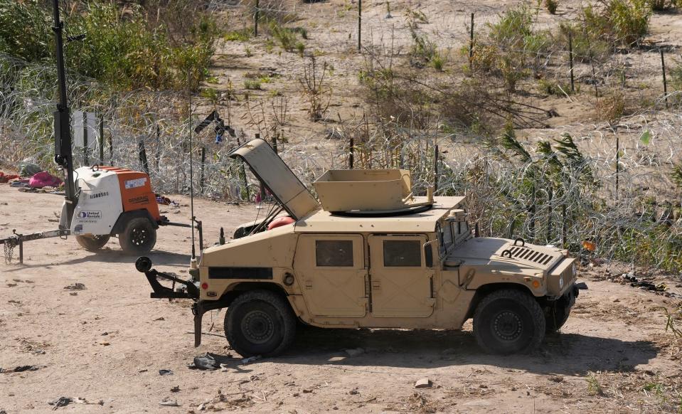 A Texas National Guard Humvee is parked next to concertina wire in Shelby Park in Eagle Pass. The state and federal governments have been at odds over Texas' deployment of the razor wire along the border.