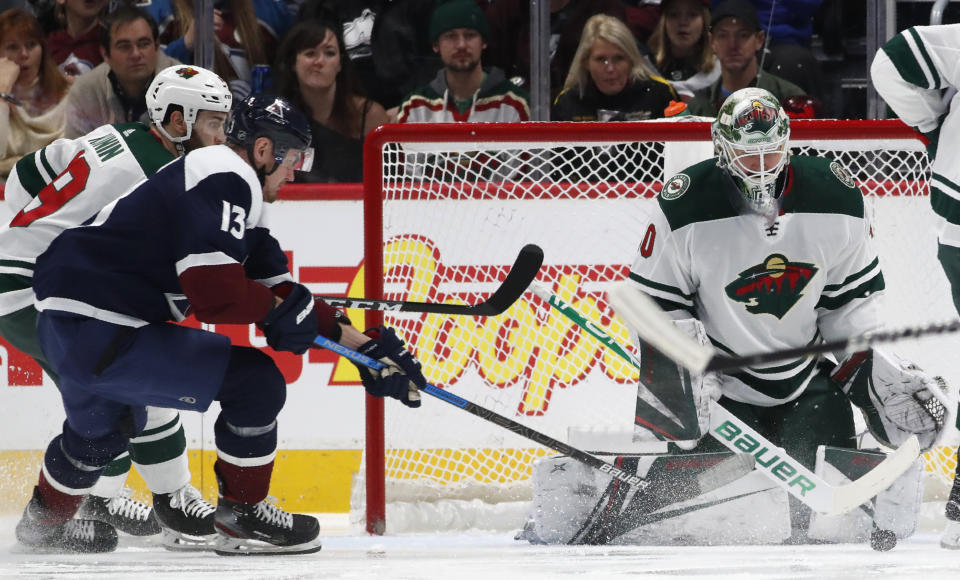 Minnesota Wild goaltender Devan Dubnyk, right, stops a redirected shot off the stick of Colorado Avalanche right wing Valeri Nichushkin, front left, who drives past Wild center Luke Kunin to the net in the second period of an NHL hockey game Friday, Dec. 27, 2019, in Denver. (AP Photo/David Zalubowski)