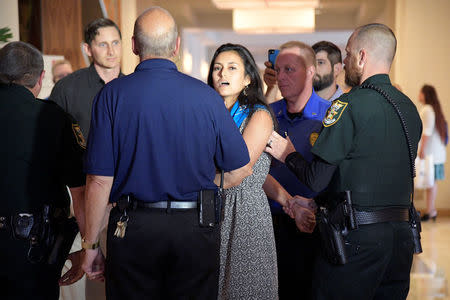 A protester (C) is escorted away from a Wells Fargo annual shareholder meeting by hotel security and police officers in Jacksonville, Florida, U.S., April 25, 2017. REUTERS/Phelan Ebenhack