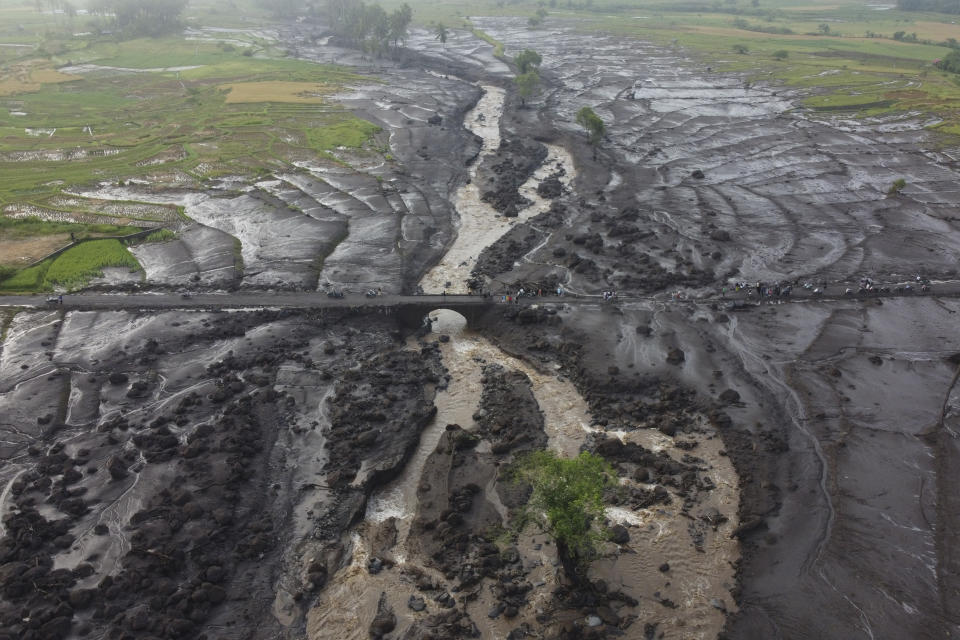 People examine the damage at an area badly affected by a flash flood in Tanah Datar, West Sumatra, Indonesia, Monday, May 13, 2024. Heavy rains and torrents of cold lava and mud flowing down a volcano's slopes on Indonesia's Sumatra island triggered flash floods causing a number of people dead and missing, officials said Sunday. (AP Photo/Ali Nayaka)