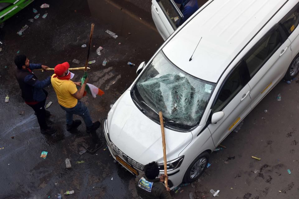 NEW DELHI, INDIA - JANUARY 26: Farmers vandalise vehicles following a clash with Delhi Police during the tractor march from Tikri border, at Nagloi Crossing, on January 26, 2021 in New Delhi, India. Major scenes of chaos and mayhem at Delhi borders as groups of farmers allegedly broke barricades and police check posts and entered the national capital before permitted timings. Police used tear gas at Delhi's Mukarba Chowk to bring the groups under control. Clashes were also reported at ITO, Akshardham. Several rounds of talks between the government and protesting farmers have failed to resolve the impasse over the three farm laws. The kisan bodies, which have been protesting in the national capital for almost two months, demanding the repeal of three contentious farm laws have remained firm on their decision to hold a tractor rally on the occasion of Republic Day.(Photo by Raj K Raj/Hindustan Times via Getty Images)