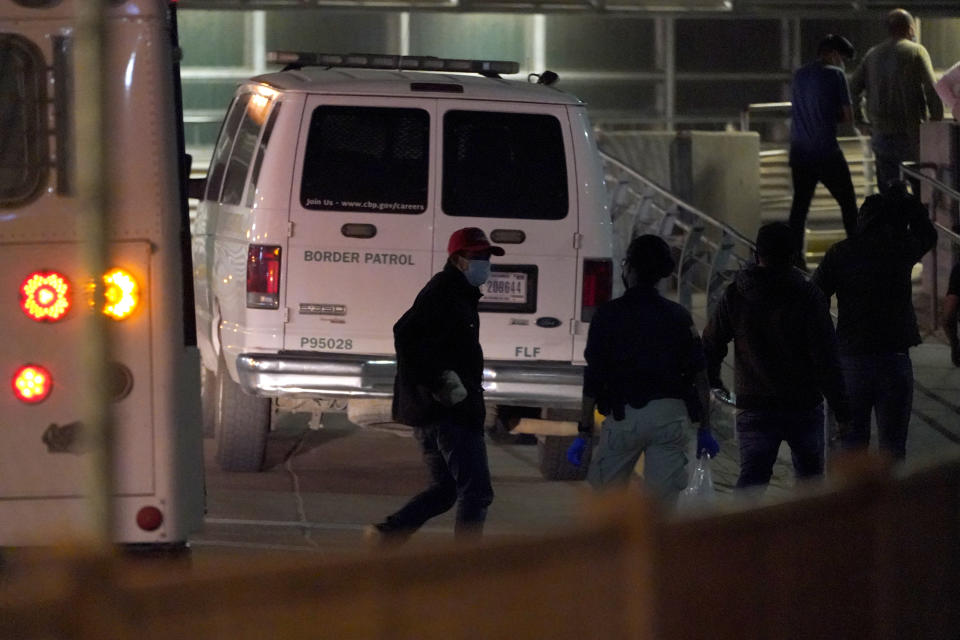 An official, second from left, looks on as migrants are deported to Mexico at the McAllen-Hidalgo International Bridge, Saturday, March 20, 2021, in Hidalgo, Texas. The fate of thousands of migrant families who have recently arrived at the Mexico border is being decided by a mysterious new system under President Joe Biden. U.S. authorities are releasing migrants with “acute vulnerabilities” and allowing them to pursue asylum. But it’s not clear why some are considered vulnerable and not others. (AP Photo/Julio Cortez)