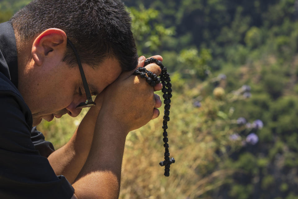 Lebanese priest Hani Tawk prays outside the Qannoubine Monastery, hidden deep in the Kadisha Valley, a holy site for Lebanon's Maronite Christians, in the northeast mountain town of Bcharre, Lebanon, Saturday, July 22, 2023. For Lebanon's Christians, the cedars are sacred, these tough evergreen trees that survive the mountain's harsh snowy winters. They point out with pride that Lebanon's cedars are mentioned 103 times in the Bible. (AP Photo/Hassan Ammar)