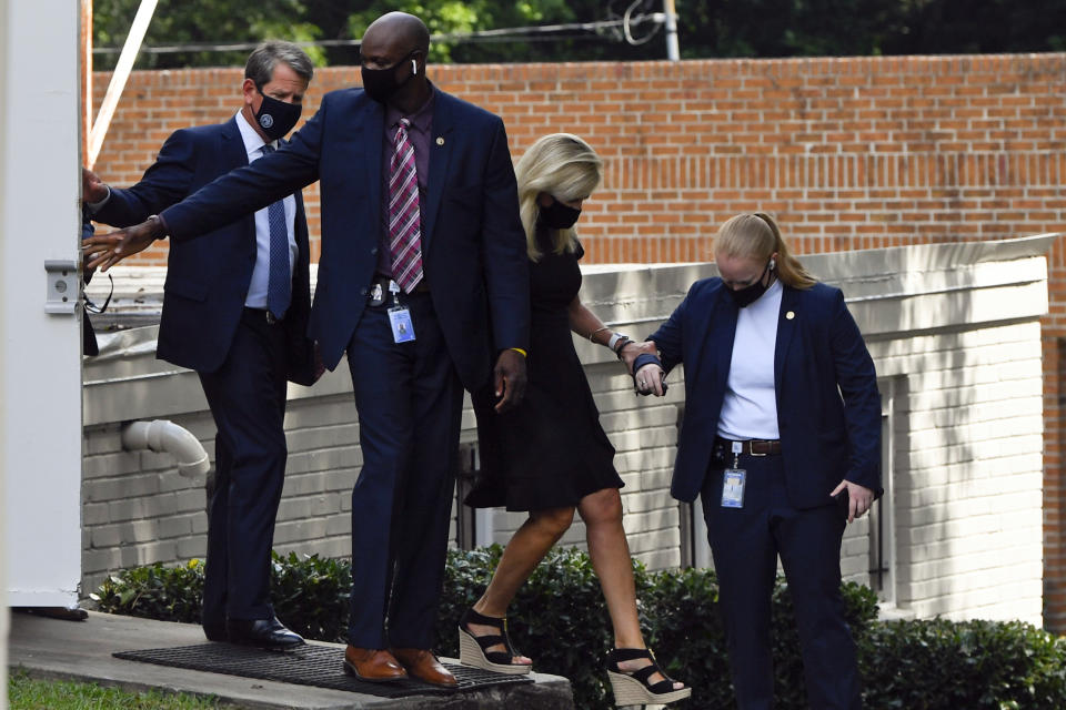 Georgia Gov. Brian Kemp, left, leaves a private viewing for Herman Cain, Thursday, Aug. 6, 2020 in Atlanta. Cain, a former Republican presidential candidate, radio host, and entrepreneur died on July 30, after being hospitalized with COVID-19 and will be laid to rest this week. He was 74. (AP Photo/John Amis)