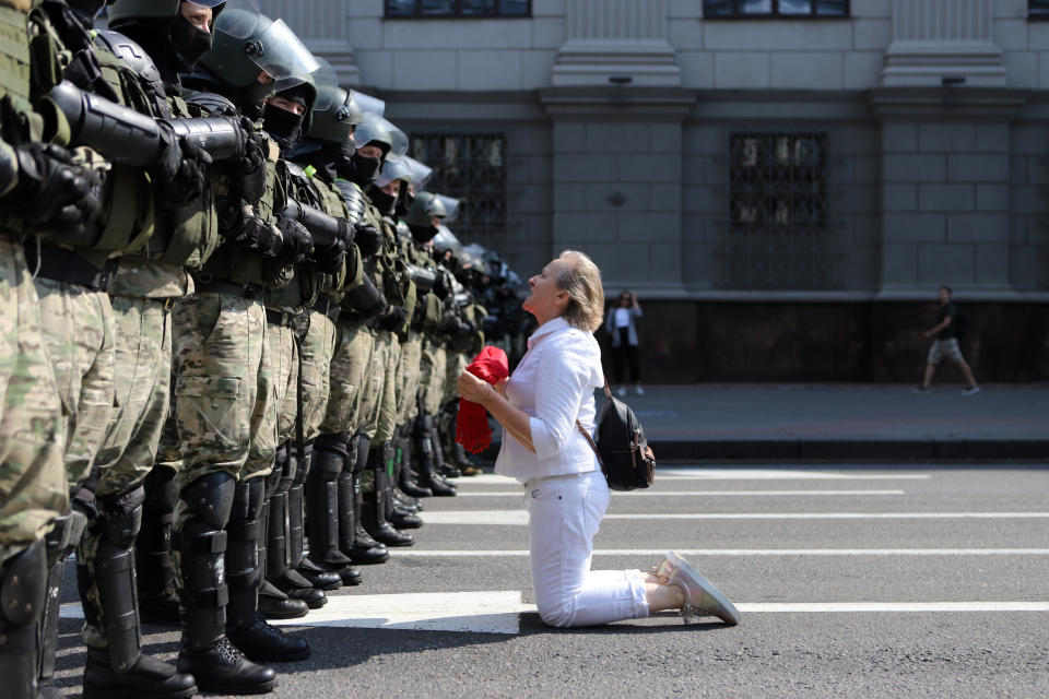 A woman kneels in front of a riot police line as they block Belarusian opposition supporters rally in the center of Minsk, Belarus, Sunday, Aug. 30, 2020. Opposition supporters whose protests have convulsed the country for two weeks aim to hold a march in the capital of Belarus. (AP Photo)