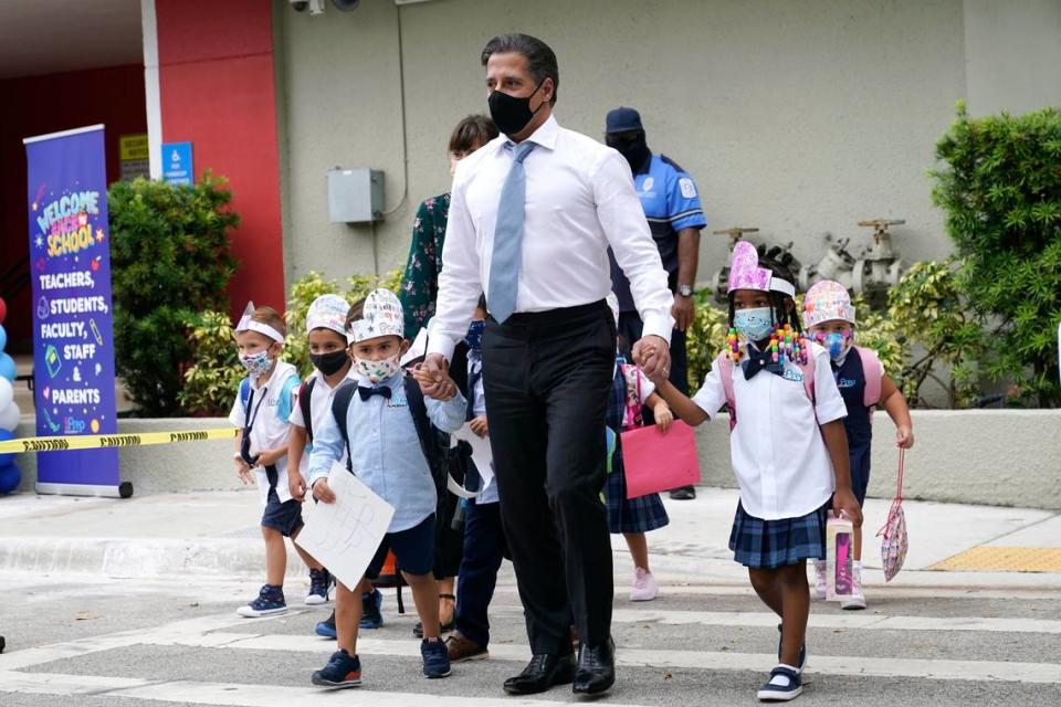 Miami-Dade schools Superintendent Alberto Carvalho, center, walks with students Oliver Angel, left, and Ariah Olawale, right, outside of iPrep Academy on the first day of school, Monday, Aug. 23, 2021, in Miami. Schools in Miami-Dade County opened Monday with a strict mask mandate to guard against coronavirus infections.