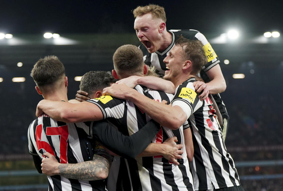 Newcastle United's Fabian Schar, center obscured, is mobbed by his team mates after scoring his sides second goal of the game during their English Premier League soccer match against Aston Villa at Villa Park, Birmingham, England, Tuesday, Jan. 30, 2024. (Jacob King/PA via AP)