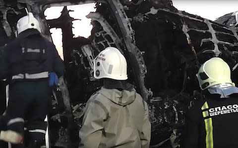 Firefighters work near the burned fuselage at Sheremetyevo airport - Credit: Russian investigative committee/TASS/Barcroft