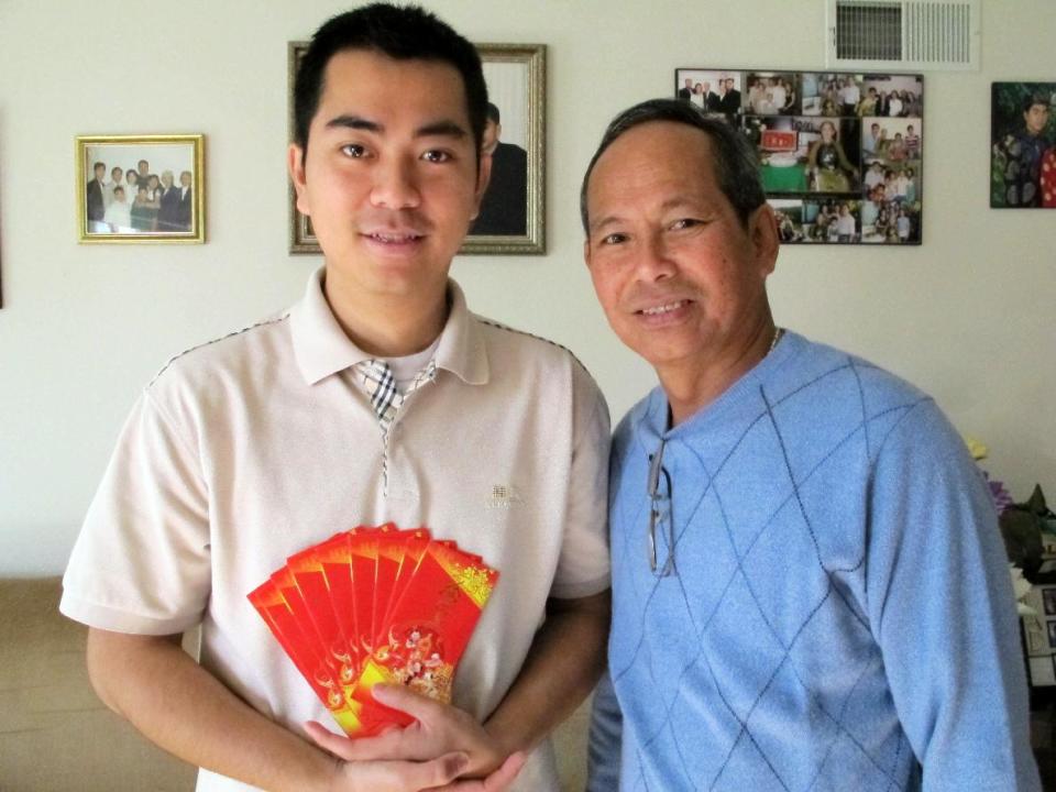 This Jan. 2, 2014 photo shows Billy Le, 26, and his father Tong Le, 61, in their Garden Grove, calif., home holding the slender red envelopes used to give out lucky money to family and friends during the Vietnamese Lunar New Year. The Vietnamese community in Orange County's Little Saigon will celebrate starting Jan. 31 with festivals, firecrackers and special foods. (AP Photo/Amy Taxin)