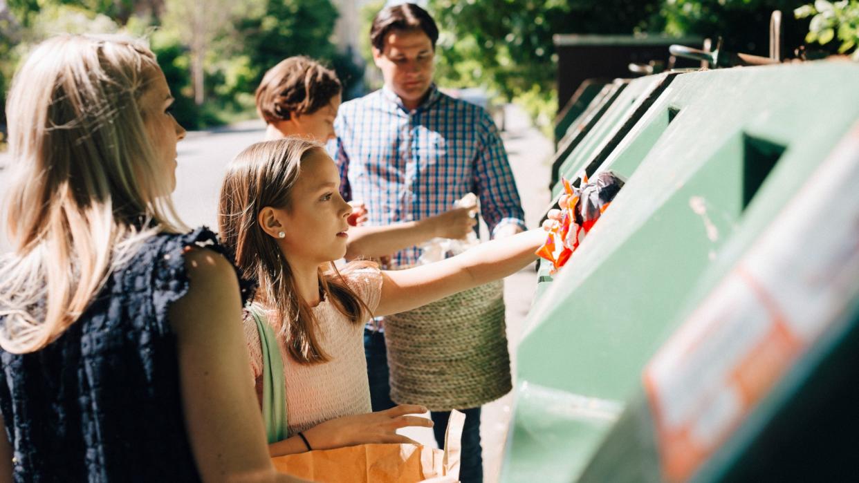  Family and children throwing garbage in bin at roadside. 