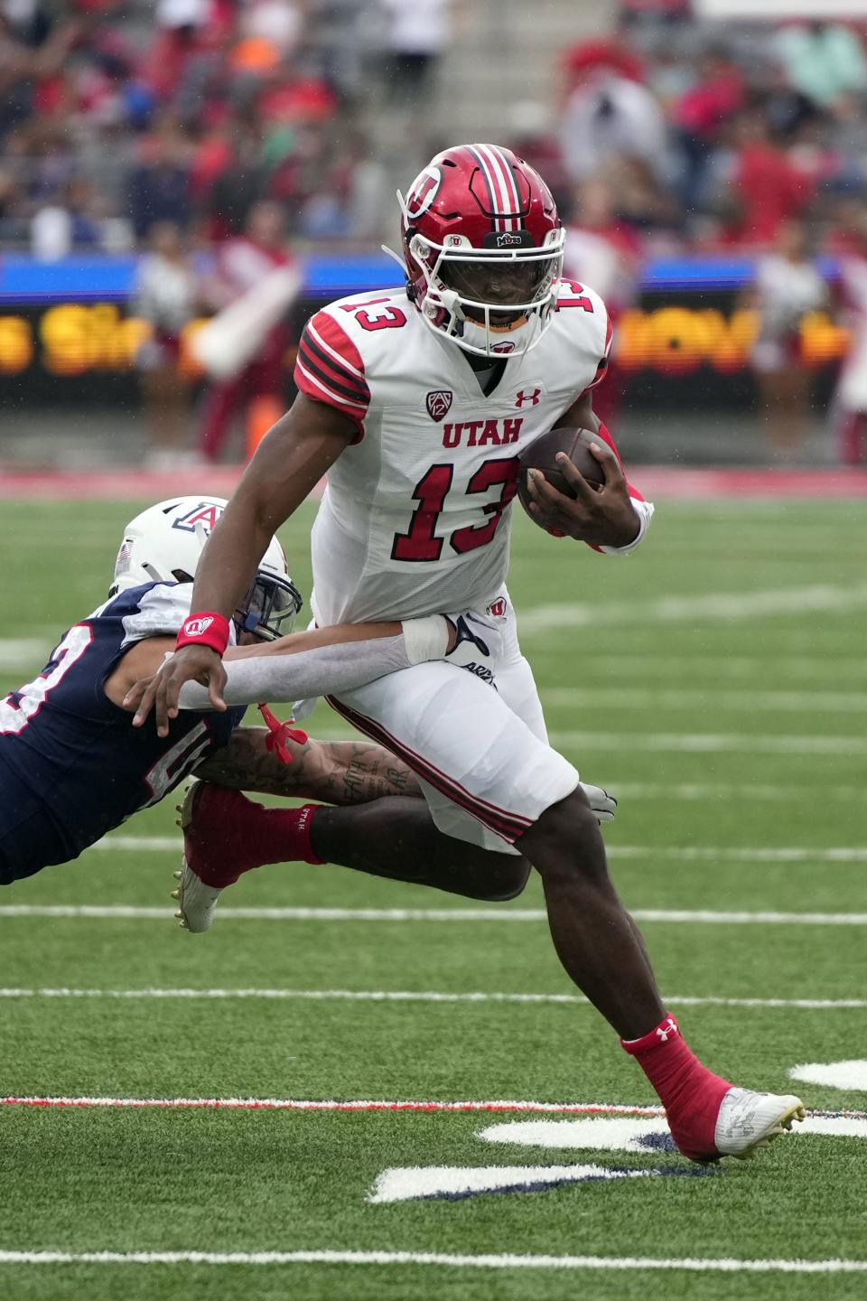 Utah quarterback Nate Johnson (13) runs away from Arizona safety Dalton Johnson during an NCAA college football game, Saturday, Nov. 18, 2023, in Tucson, Ariz. | Rick Scuteri, Associated Press