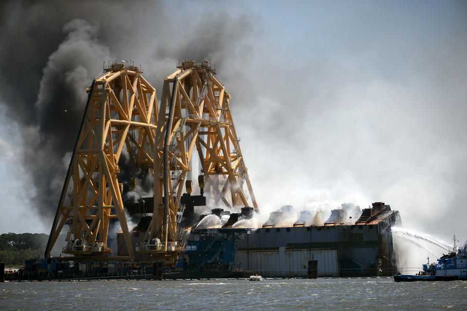 Firefighters hose down a fire in the remains of the overturned cargo ship Golden Ray, Friday, May 14, 2021, Brunswick, Ga. The Golden Ray had roughly 4,200 vehicles in its cargo decks when it capsized off St. Simons Island on Sept. 8, 2019. Coast Guard Petty Officer 2nd Class Michael Himes says there have been no injuries and all demolition crew members were safely evacuated. (AP Photo/Stephen B. Morton)