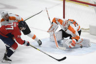 Philadelphia Flyers goaltender Alex Lyon (34) stops the puck against Washington Capitals right wing T.J. Oshie (77) during the second period of an NHL hockey game, Saturday, May 8, 2021, in Washington. Flyers defenseman Cam York is at top left. (AP Photo/Nick Wass)