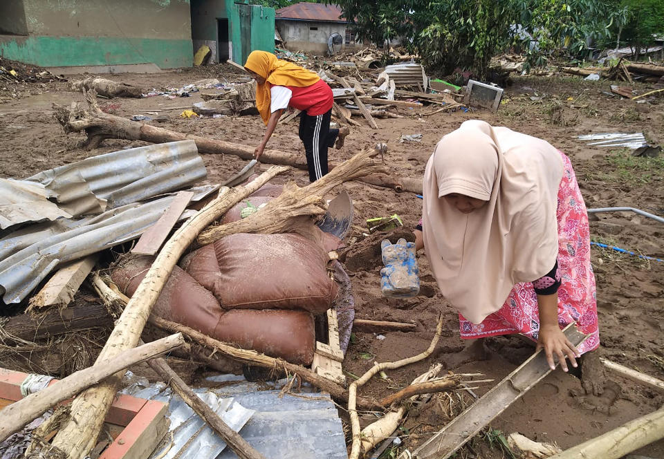 Women clear flood debris in the village in Waiwerang, on Adonara Island, easter Indonesia, Tuesday, April 6, 2021. Rescuers in remote eastern Indonesia were digging through the debris of a landslide Tuesday in search of people believed to be buried in one of several disasters brought on by severe weather in the Southeast Asian nation and neighboring East Timor. (AP Photo/Rofinus Monteiro)