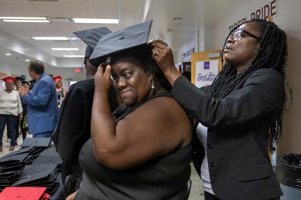 Dawn Chandler, right, helps Teressa Parker don her cap prior to the Parent University graduation at Pensacola High School on Thursday.
