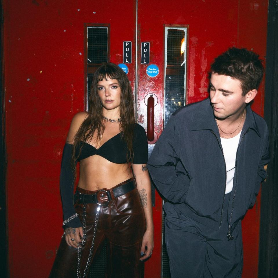 a man and woman standing in front of a red wall