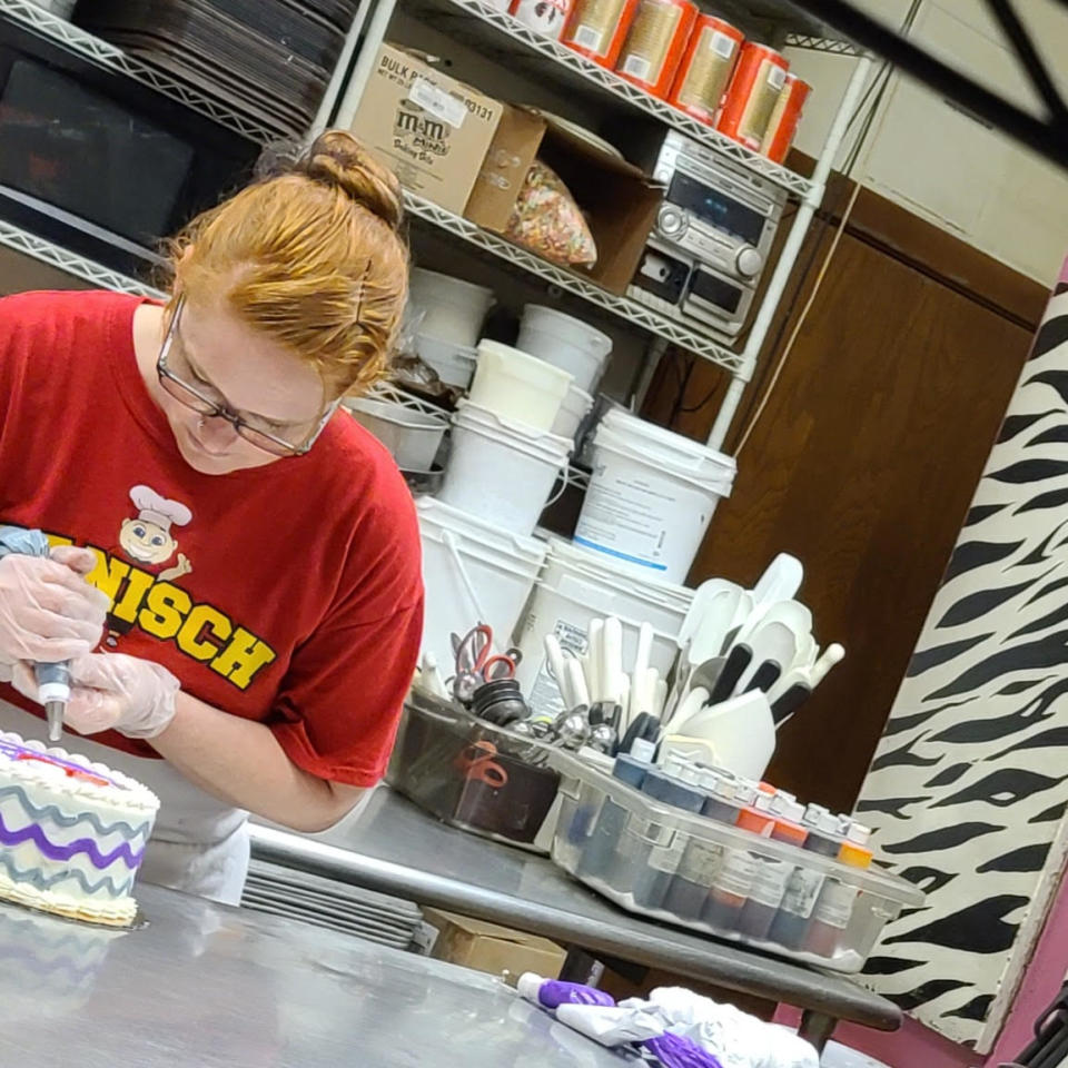 A bakery worker decorates a cake with buttercream frosting. (Bill Hanisch)