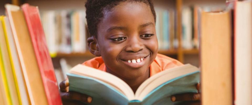 Cute little boy reading book in the library