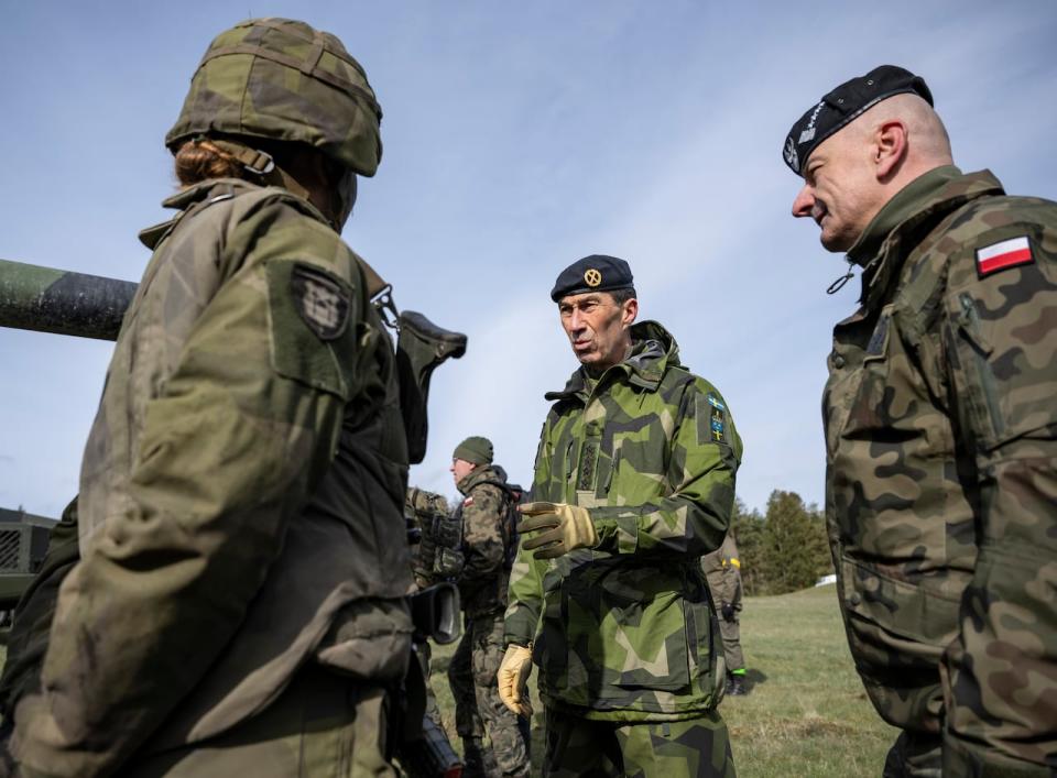 Sweden's Commander-in-Chief Micael Byden, centre, and Poland's Commander-in-Chief General Rajmund Andrzejczak, right, talk to conscripted tank crews during the Aurora 23 military exercise at the Rinkaby firing range outside Kristianstad, Sweden on May 6, 2023.