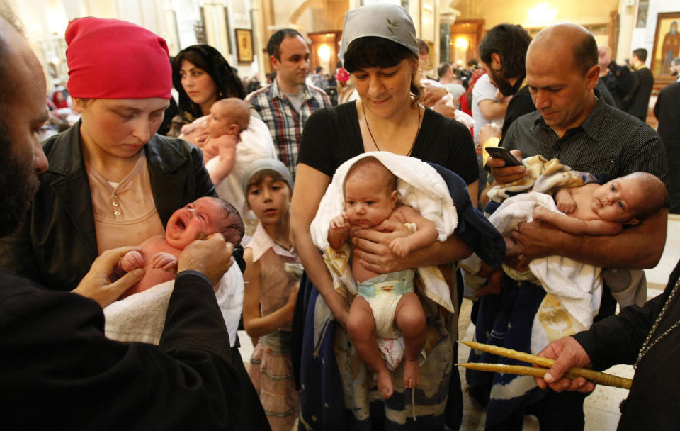 Georgian babies are baptized at the Holy Trinity Cathedral in Tbilisi, Georgia on Sunday, May 6, 2012. Many of the parents of the 400 babies baptized on Sunday said Georgian Orthodox Church Patriarch Ilia II was instrumental in their decision to have a third or fourth child. Patriarch Ilia II promised to become the godfather of all babies born into Orthodox Christian families who already have two or more children and since 2008 has gained nearly 11,000 godchildren. (AP Photo/ Shakh Aivazov)