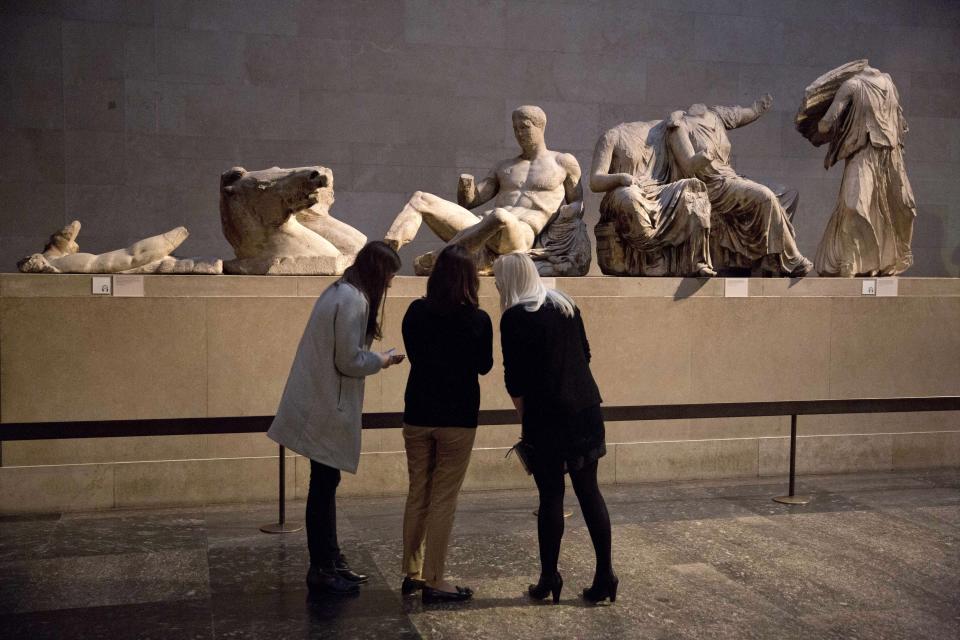 FILE - Women stand by a marble statue of a naked youth thought to represent Greek god Dionysos, center, from the east pediment of the Parthenon, on display during a media photo opportunity to promote a forthcoming exhibition on the human body in ancient Greek art at the British Museum in London on Jan. 8, 2015. Greece's prime minister said Thursday May 11, 2023 his government is exploring a “win-win” solution to one of the world’s most intractable cultural heritage disputes: The fate of the Parthenon Sculptures currently in the British Museum. (AP Photo/Matt Dunham, File)