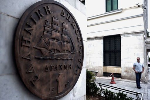 A man stands near a monument featuring a replica of the last edition of the Greek currency, the drachma. Greece's president called Monday for talks on a technocrat government, seeking to resolve the crisis over a tough EU-IMF debt bailout which risks forcing the country into new elections and out of the eurozone