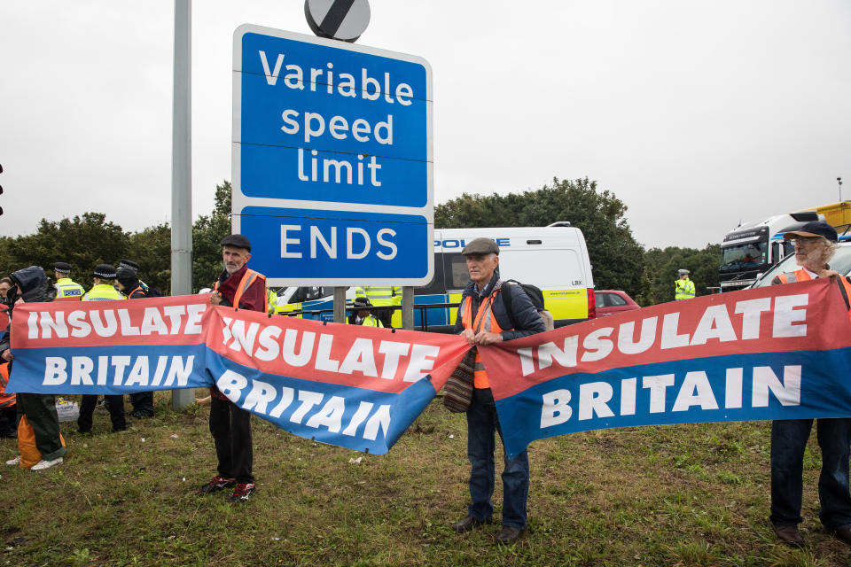 Insulate Britain climate activists hold banners after a M25 slip road at Junction 14 close to Heathrow airport was blocked as part of a campaign intended to push the UK government to make significant legislative change to start lowering emissions on 27th September 2021 in Colnbrook, United Kingdom. The activists are demanding that the government immediately promises both to fully fund and ensure the insulation of all social housing in Britain by 2025 and to produce within four months a legally binding national plan to fully fund and ensure the full low-energy and low-carbon whole-house retrofit, with no externalised costs, of all homes in Britain by 2030. (photo by Mark Kerrison/In Pictures via Getty Images)