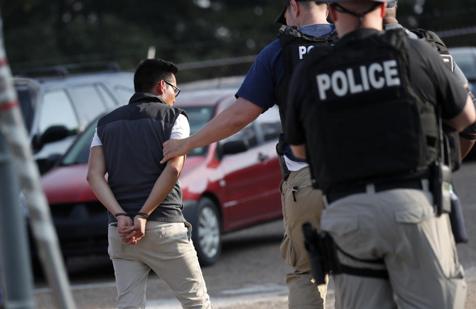 A man is taken into custody at a Koch Foods Inc. plant in Morton, Miss., on Wednesday, Aug. 7, 2019. U.S. immigration officials raided several Mississippi food processing plants on Wednesday and signaled that the early-morning strikes were part of a large-scale operation targeting owners as well as employees. (AP Photo/Rogelio V. Solis)