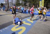 A runner toward the back of the fourth and last wave of competitors kneels to kiss the start line as he begins his running of the 118th Boston Marathon, Monday, April 21, 2014, in Hopkinton, Mass. (AP Photo/Stephan Savoia)