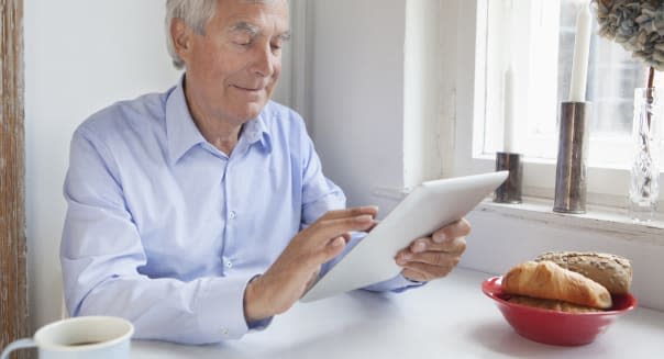 Senior man using digital tablet at breakfast table