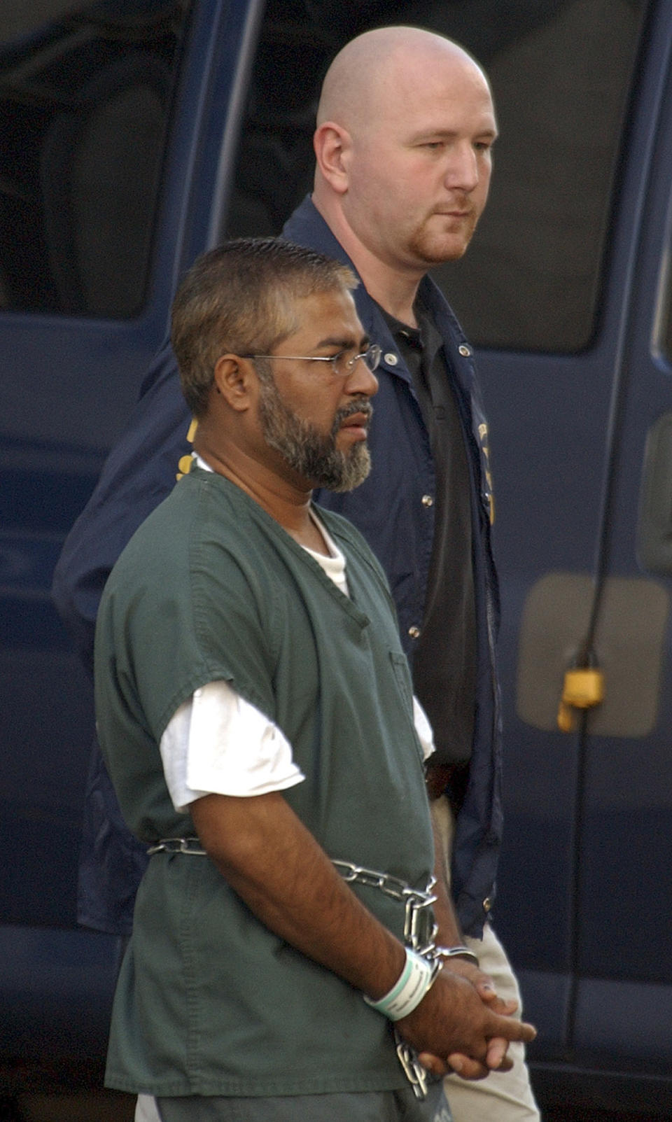 FILE - Mohammed Hossain, foreground, is escorted out of the Federal Building by a U.S. Federal Marshal, Tuesday, Aug. 24, 2004, in Albany, N.Y. The government sting was launched in the anxious years after 9/11 to catch potential terrorists. But critics accused FBI agents of using a manipulative informant to ensnare people. In a scathing ruling, a judge last week said the "real lead conspirator was the United States." (AP Photo/Jim McKnight, FILE)