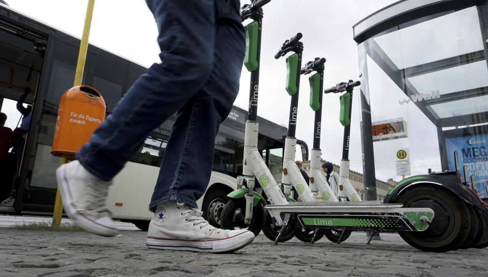 In this Friday, Sept. 13, 2019 photo a traveller walks past electric scooter as he leaves a public bus in Berlin, Germany. (AP Photo/Michael Sohn)