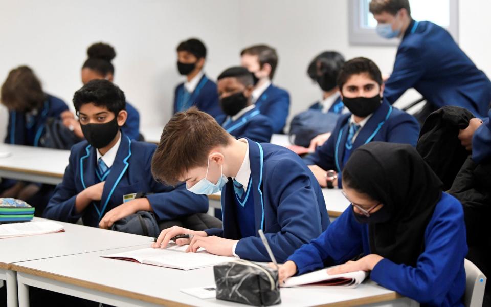 Year 9 students wear protective face masks as they take part in lessons  - Toby Melville/Reuters